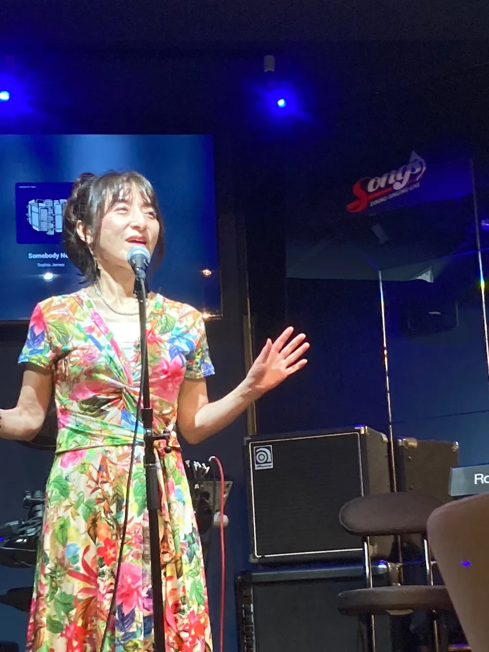 ステージのマイクの前で歌う女性。カラオケボックスではなくライブステージで歌える