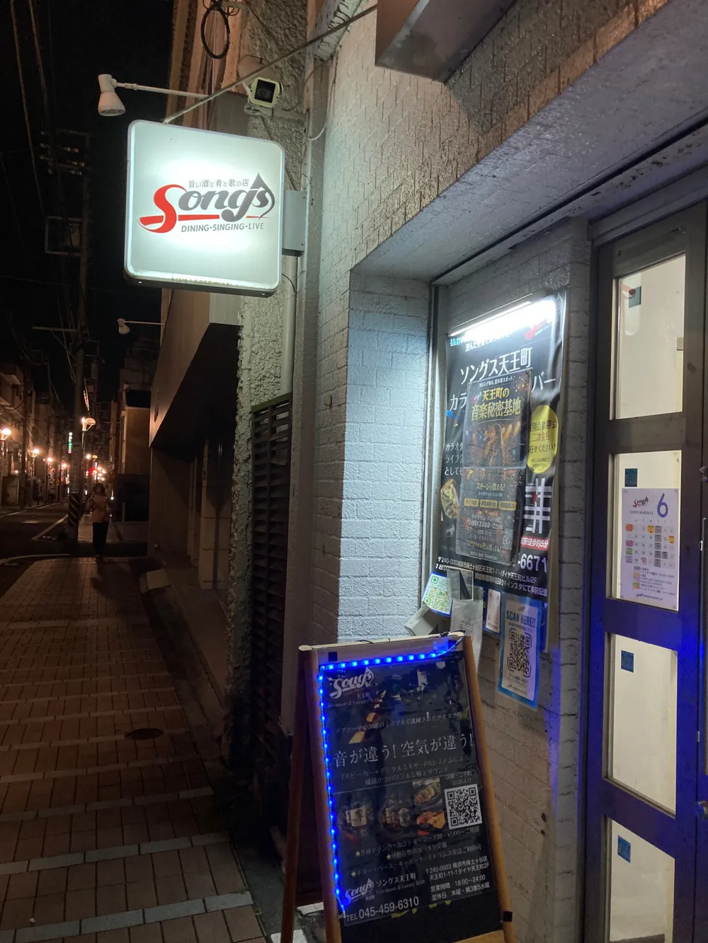 夜の店舗外観。Songsの看板が灯る入口